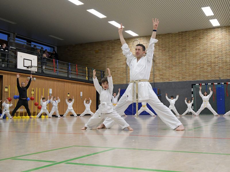 Kinder im Karate-Outfit strecken die Hände in die Höhe