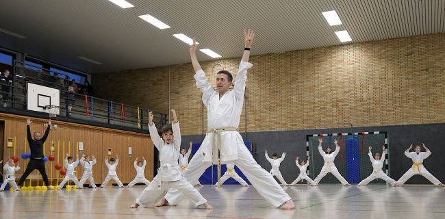 Kinder im Karate-Outfit strecken die Hände in die Höhe